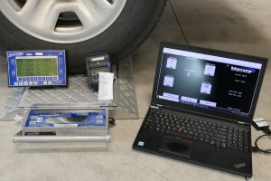 Photo contains wireless display, printer, and laptop next to in-use wheel load scale.